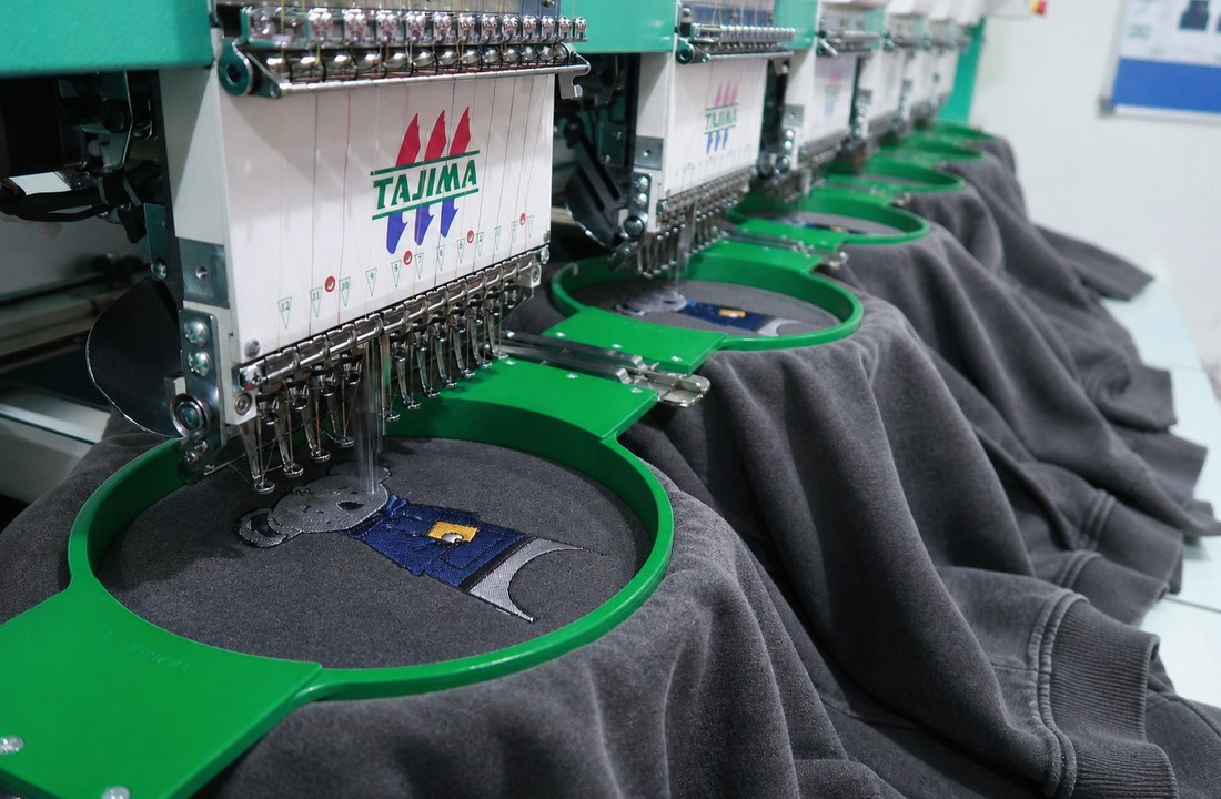 Multi-head embroidery machines decorating heavyweight hoodie panels in production