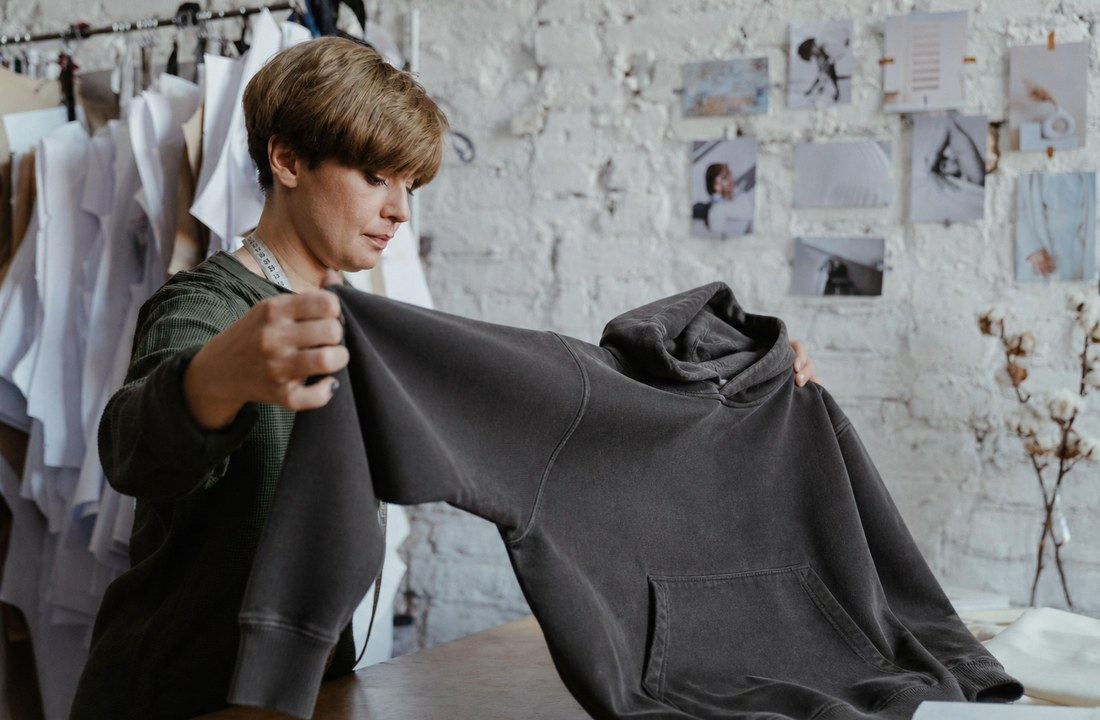Apparel worker inspecting a finished heavyweight hoodie before production approval