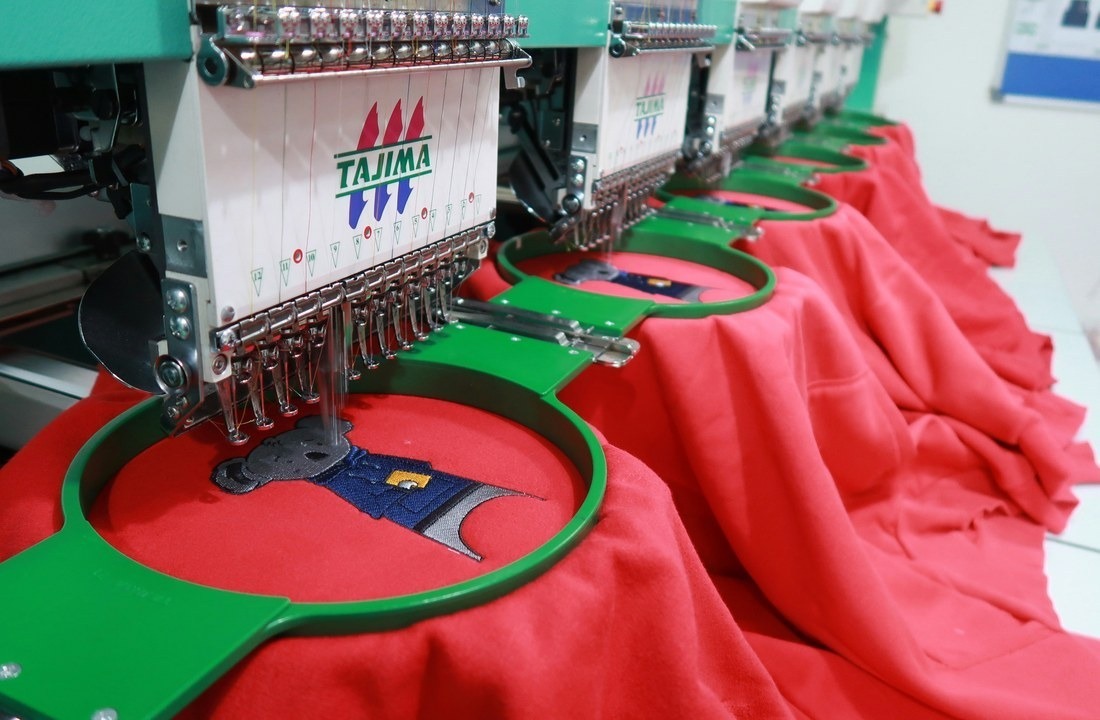 Embroidery machines decorating heavyweight knit garments for hoodie production