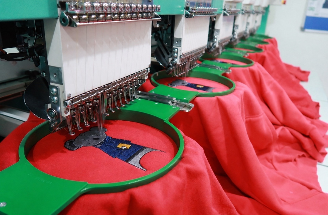 Embroidery machines decorating heavyweight knit garments for hoodie production