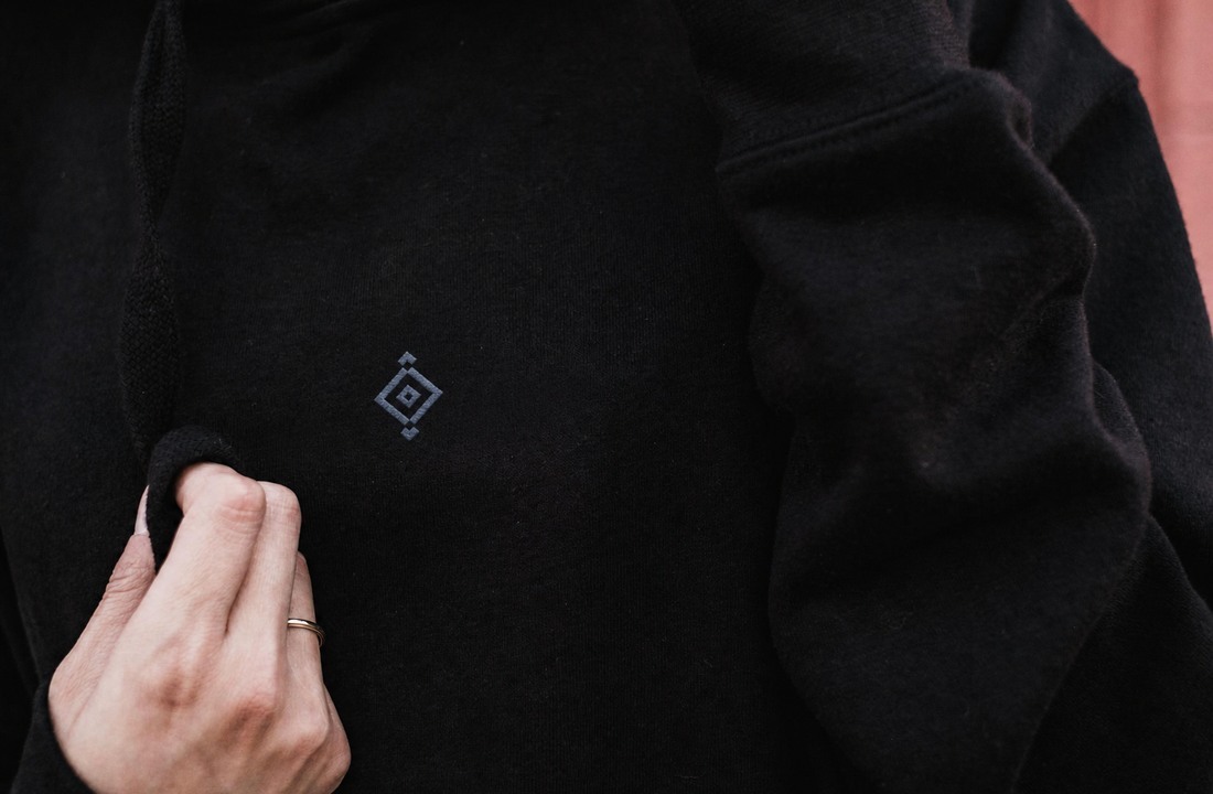 Close-up of a compact geometric embroidery sample on a black custom hoodie