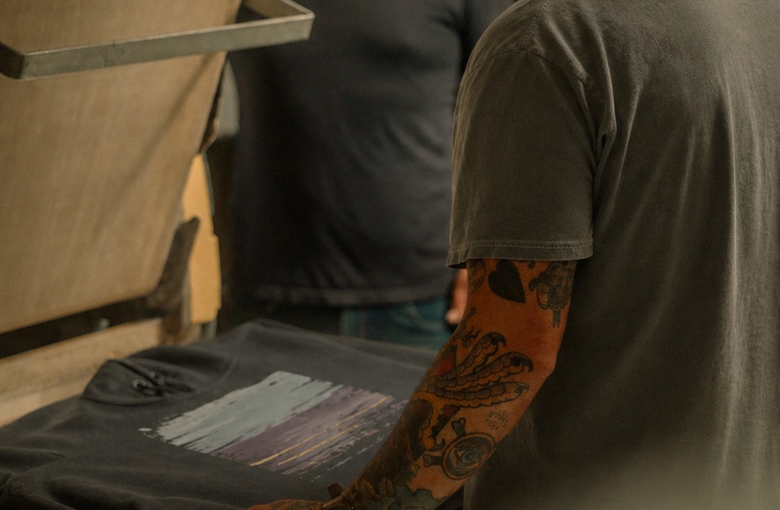 Screen printer checking an unbranded hoodie print in a garment workshop