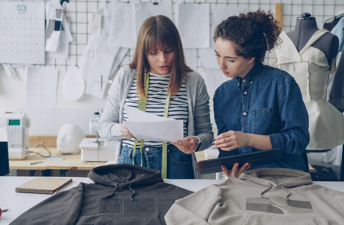Apparel developers reviewing embroidered and printed hoodie samples before production