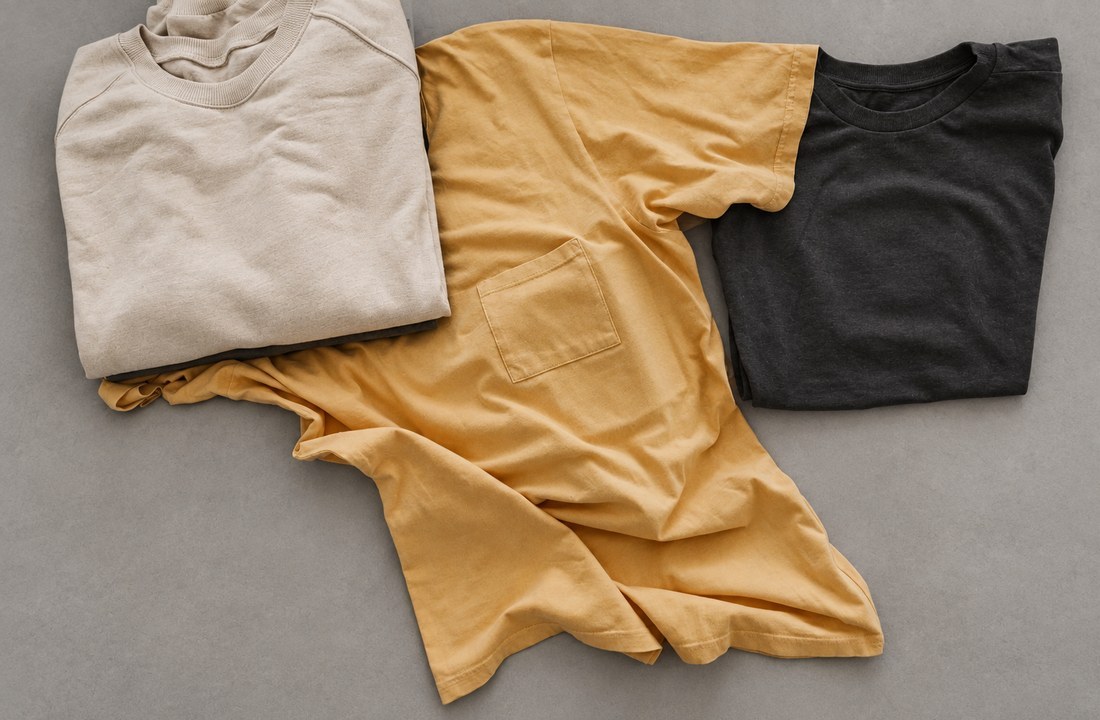 Three blank T-shirts in oatmeal ochre and charcoal compared on a neutral sourcing table