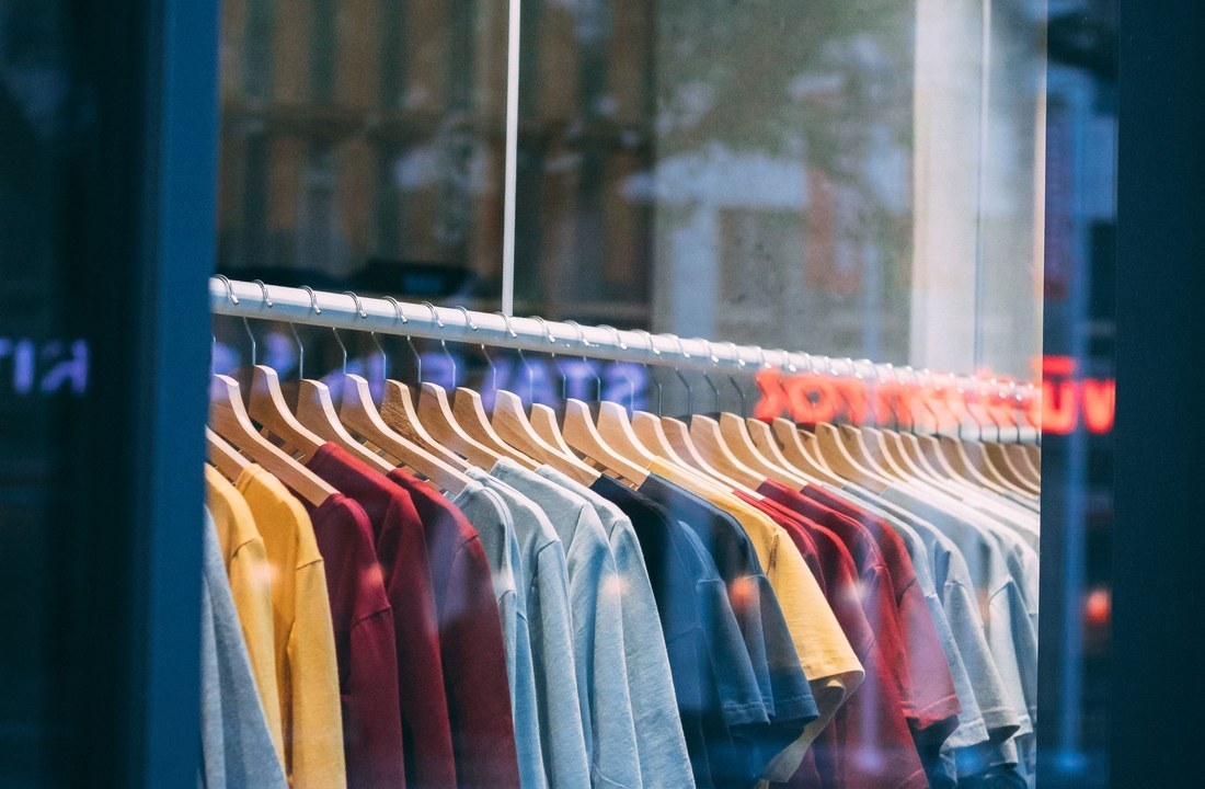 Rows of T-shirts in several colors behind a shop window