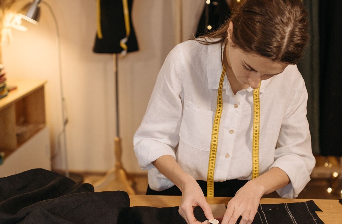 Worker cutting dark fabric on a garment worktable