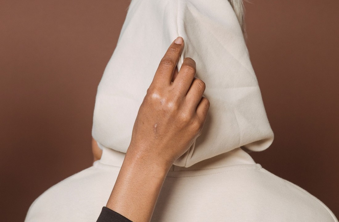 Hand adjusting the hood of a white hoodie on a model