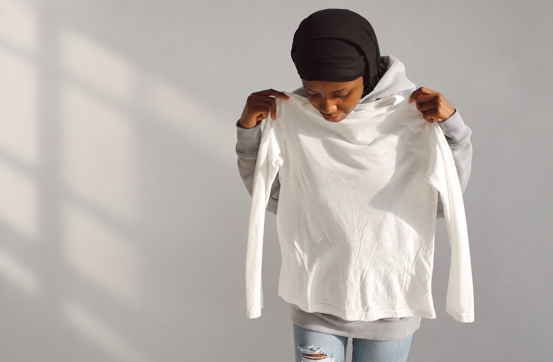 Woman holding a plain white long-sleeve top for visual review
