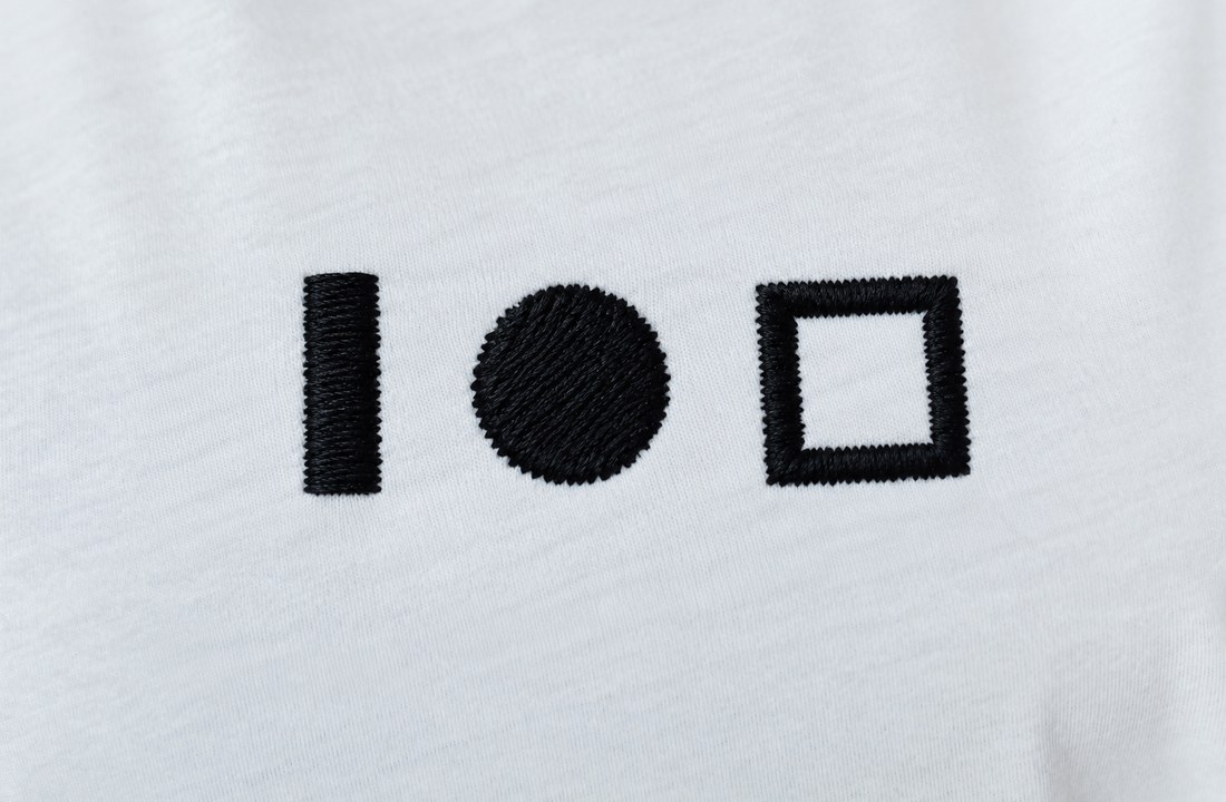 Three black embroidery stitch samples on white knit fabric