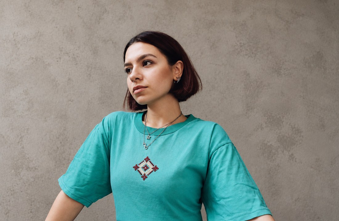 Woman wearing a turquoise T-shirt with a small geometric embroidered motif