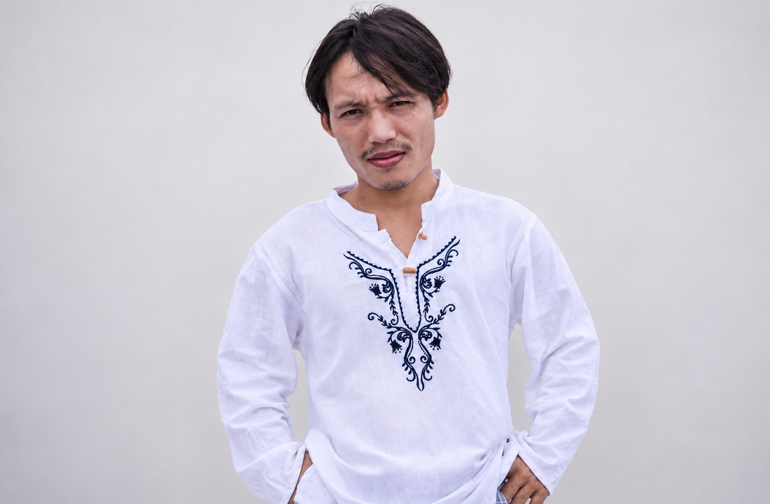 Man wearing a white long-sleeve garment with blue chest embroidery