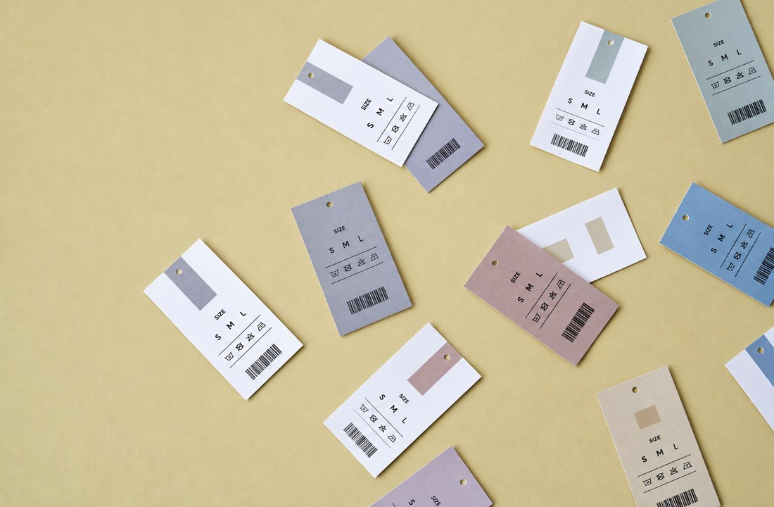 Unbranded apparel size and care tags arranged on a yellow surface